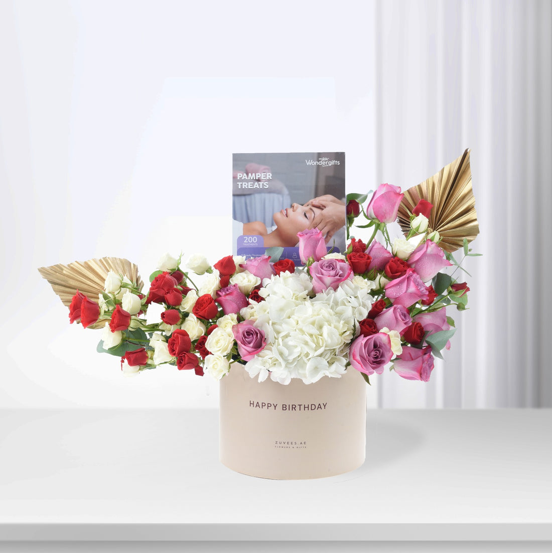 Elegant birthday bouquet with roses, hydrangeas, and gold fans in beige box.