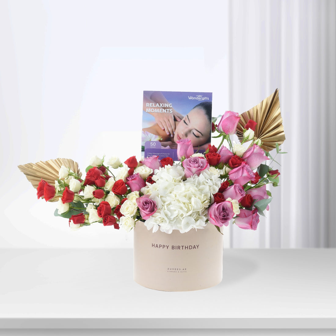 Luxury birthday bouquet with red, pink, white roses, hydrangeas, gold leaves, and spa gift card.