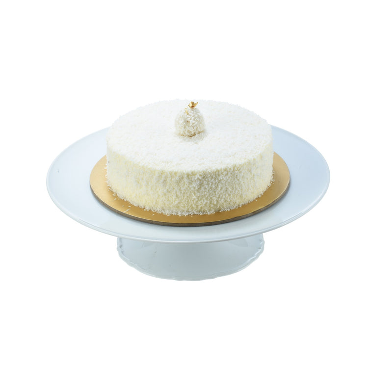 White coconut cake on gold base, topped with gold leaf, elegant presentation.