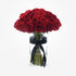 Vibrant red roses in clear glass vase, elegantly tied with black ribbon.