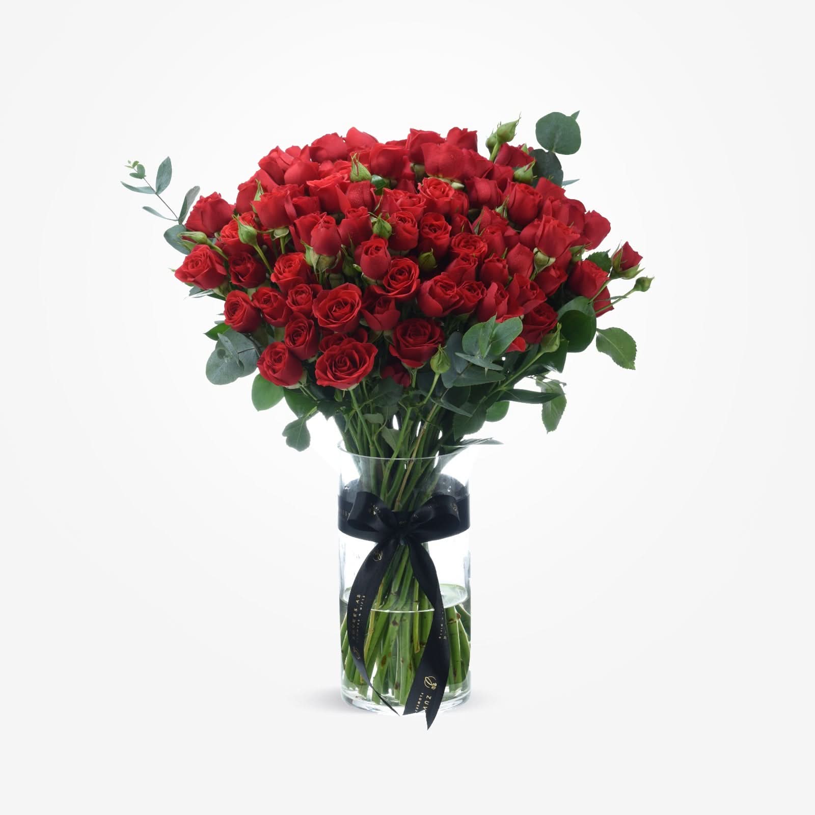Vibrant red roses in clear vase, accented with eucalyptus and black ribbon.