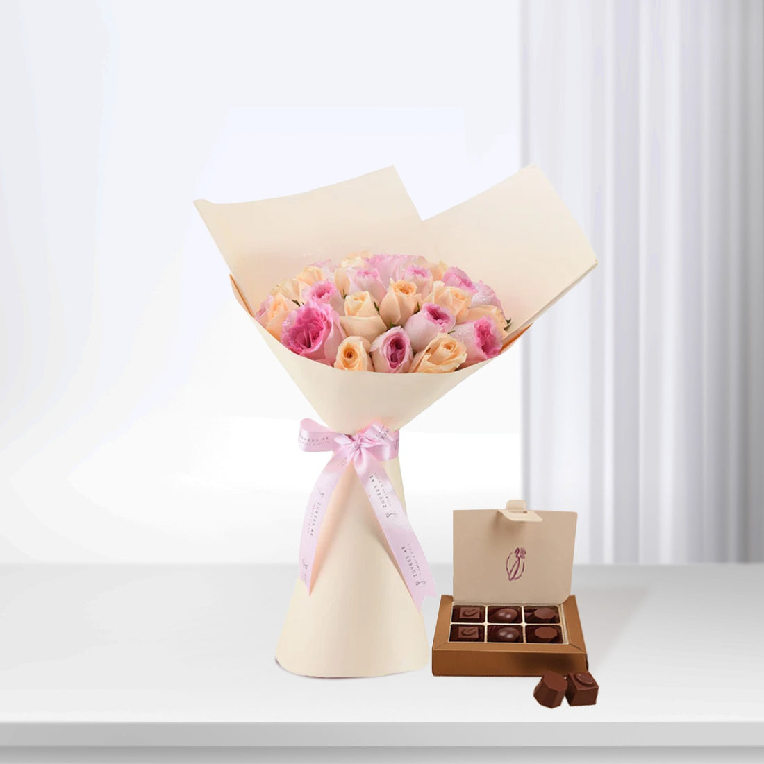 Soft pink roses wrapped elegantly with ribbon, paired with rich chocolate box.