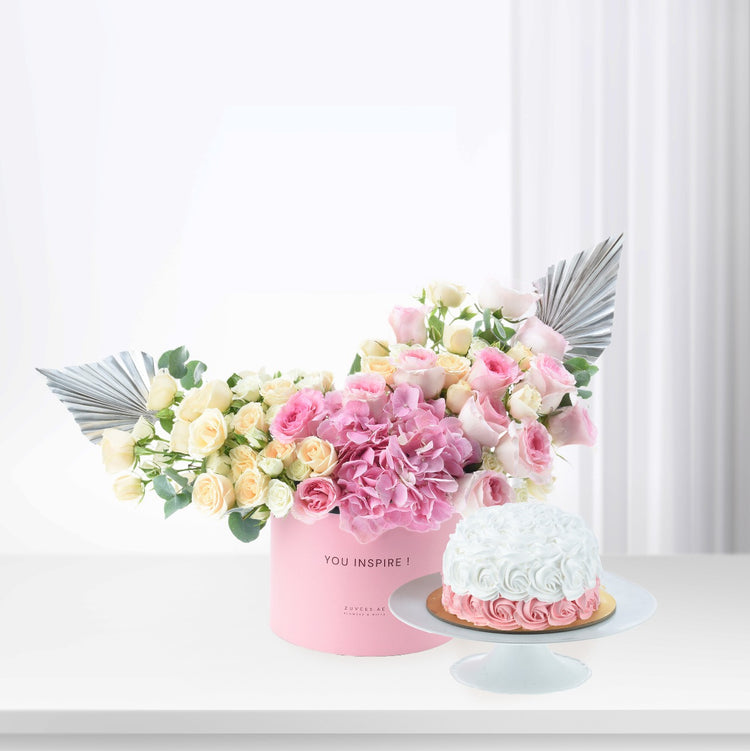 Pink floral arrangement with silver fan accents beside white-frosted cake.