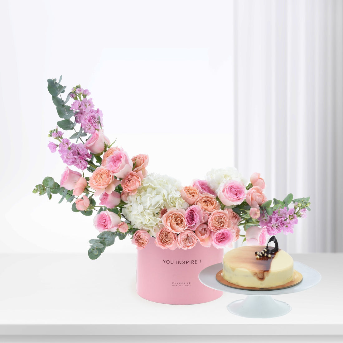 Pink floral arrangement with cake in soft, romantic hues.
