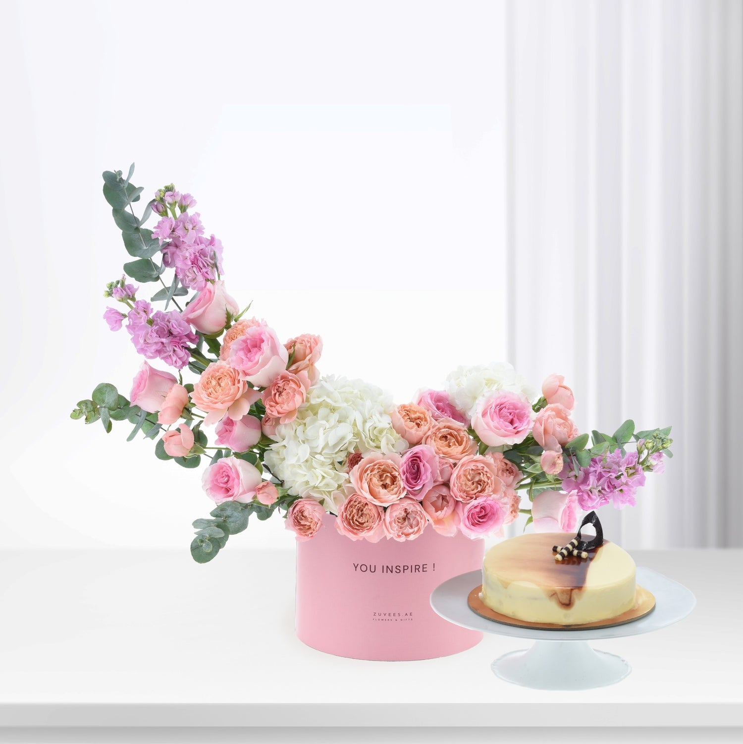 Pink floral arrangement with cake in soft, romantic hues.