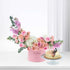 Pink floral arrangement with cake in soft, romantic hues.