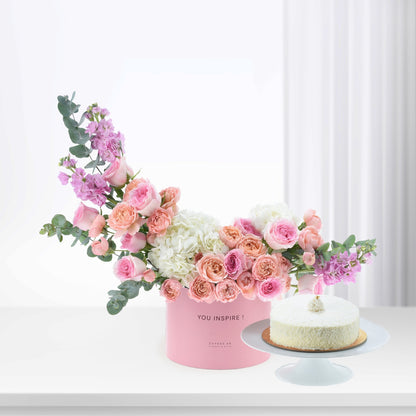 Pink floral arrangement with cake in minimalist white setting.