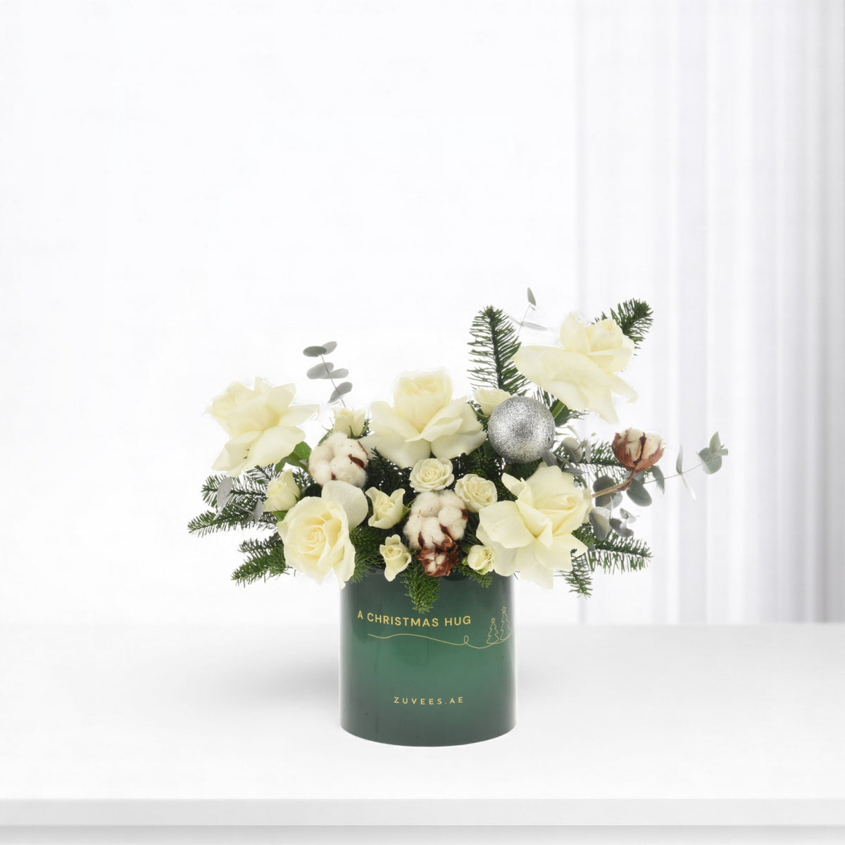 White roses, cotton, and pine in green vase with "A Christmas Hug" text.