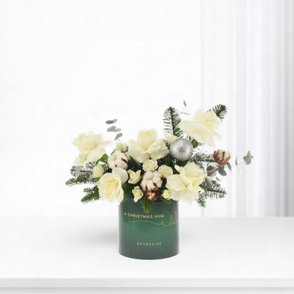 White roses, cotton, and pine in green vase with "A Christmas Hug" text.