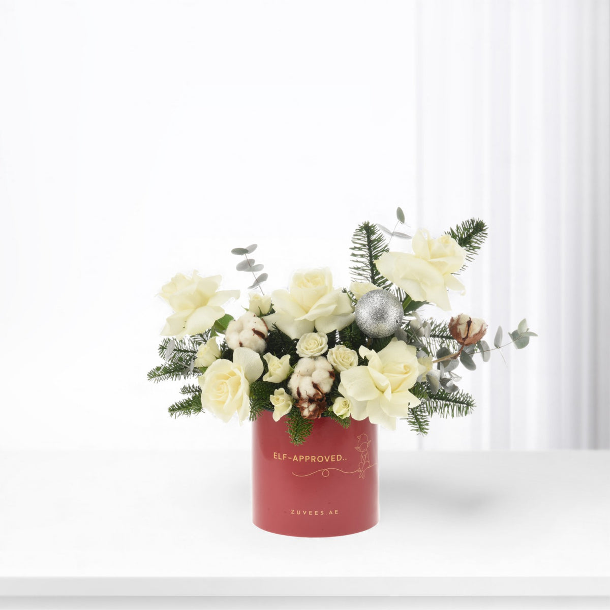 Cream roses, cotton, pine, silver bauble in festive red "Elf-Approved" Zuvees vase.