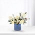 White roses, cotton, and evergreens in blue vase with silver ornament.