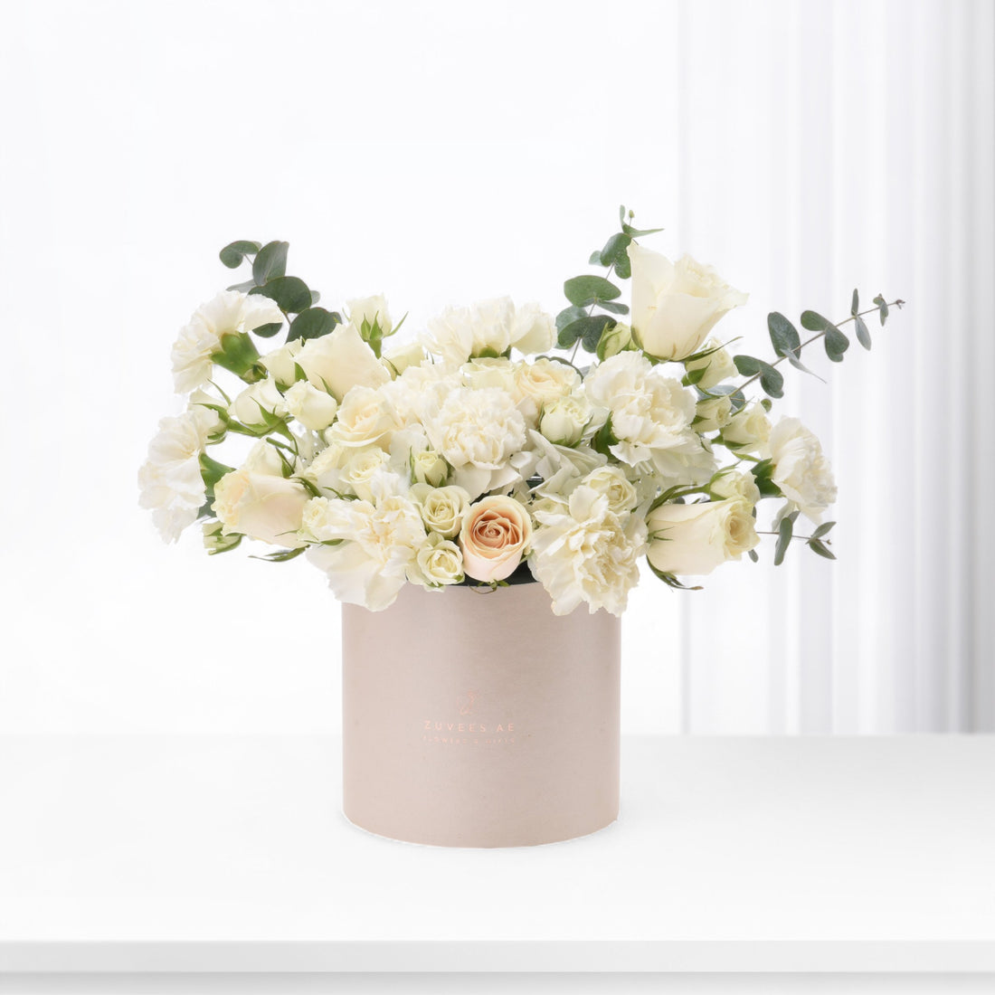 Elegant ivory roses and carnations in blush box, minimalist white backdrop.