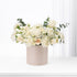 Elegant ivory roses and carnations in blush box, minimalist white backdrop.