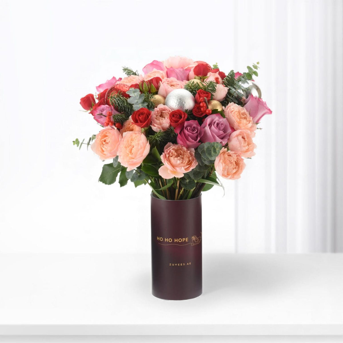 Vibrant pink, red, and purple roses in festive holiday-themed vase with "Ho Ho Hope" text.