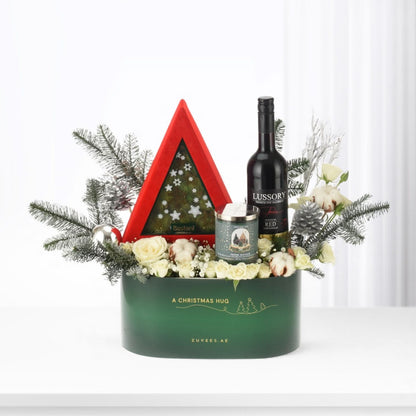 Elegant green holiday gift basket with red tree, wine, candle, and white roses.