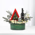 Elegant green holiday gift basket with red tree, wine, candle, and white roses.
