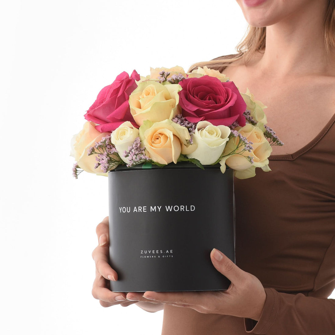 Black box holds vibrant pink, yellow, white roses with purple accents.