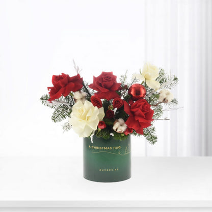 Festive red and white roses with pine, cotton, ornament in green "Christmas Hug" vase.