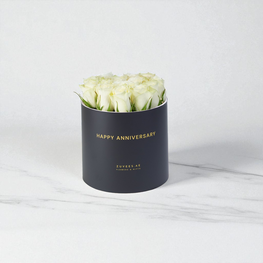 Elegant white roses in matte black box with gold "Happy Anniversary" text.