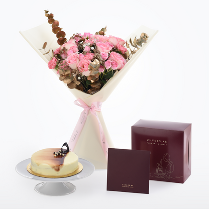 Pink rose bouquet with eucalyptus, tied with ribbon, beside cheesecake and branded gift boxes.