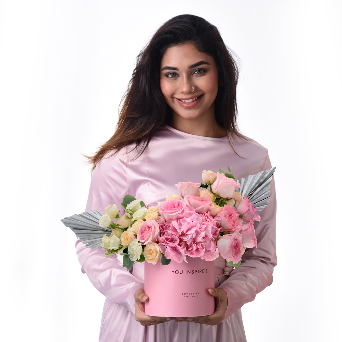Pink roses, hydrangeas in pink box with "YOU INSPIRE!" text, silver accents, held by smiling woman.