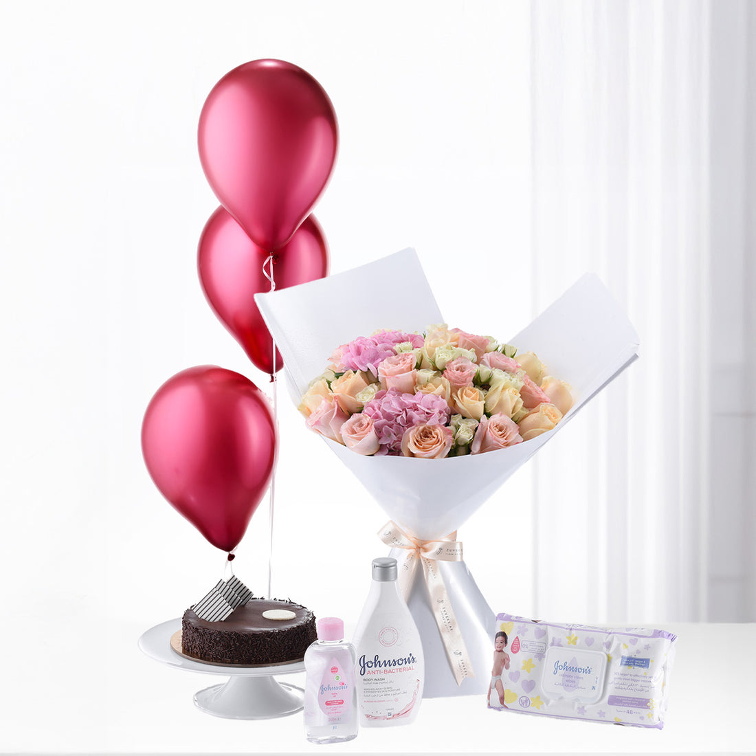 Pink roses, red balloons, baby essentials, chocolate cake—celebratory baby shower gift set.