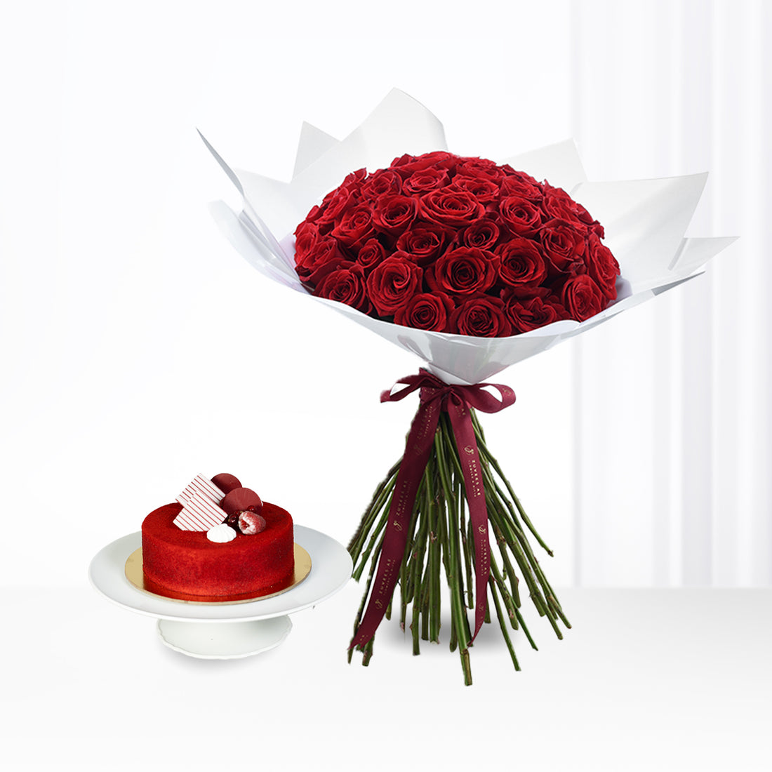 Vibrant red roses bouquet with elegant maroon ribbon, paired with a matching red velvet cake.