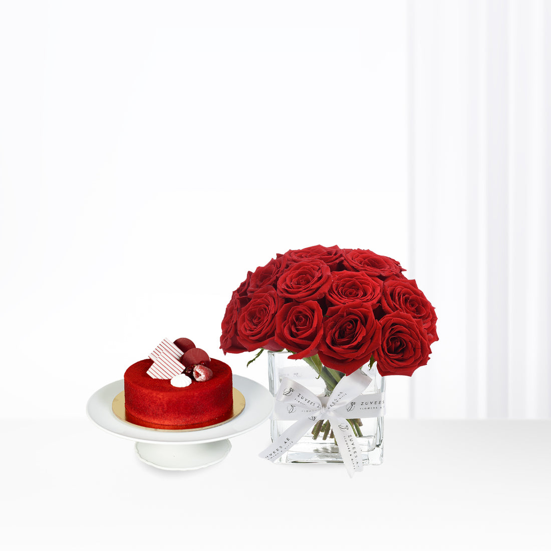 Vibrant red roses and matching cake in minimalist white setting.