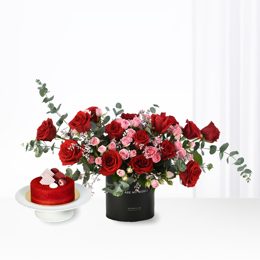 Vibrant red and pink roses with eucalyptus, paired with a red velvet cake.