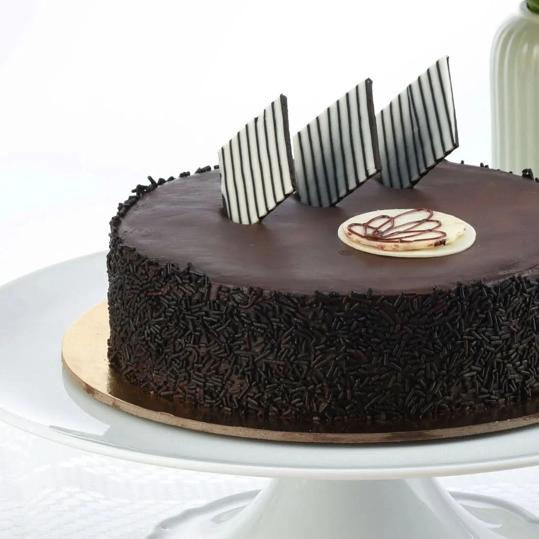 Rich chocolate cake adorned with striped chocolate shards and sprinkles.
