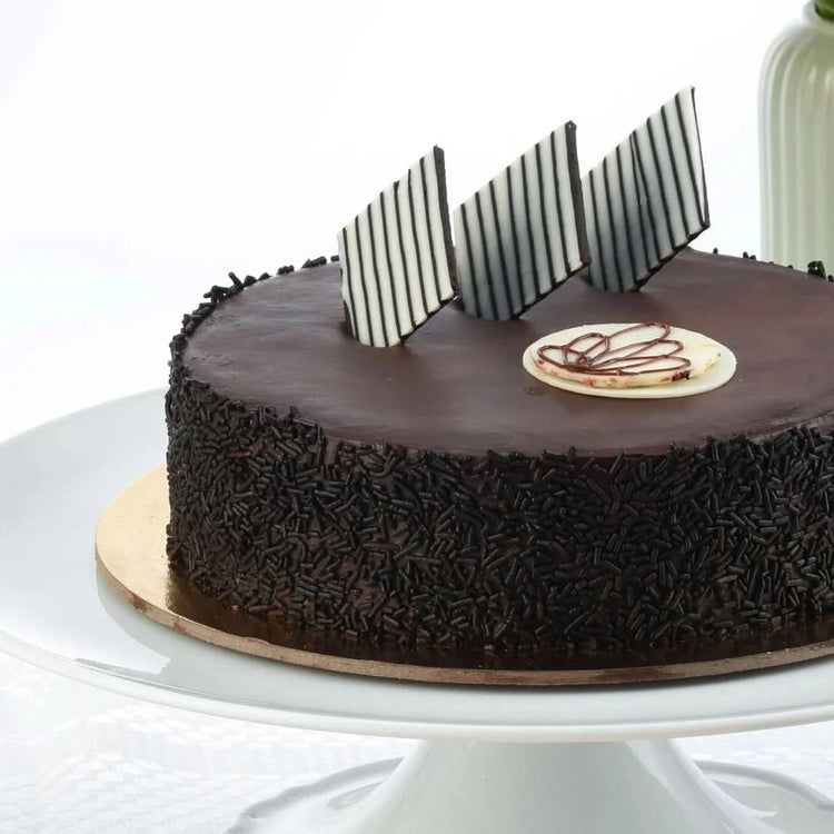 Rich chocolate cake adorned with striped chocolate shards and sprinkles.