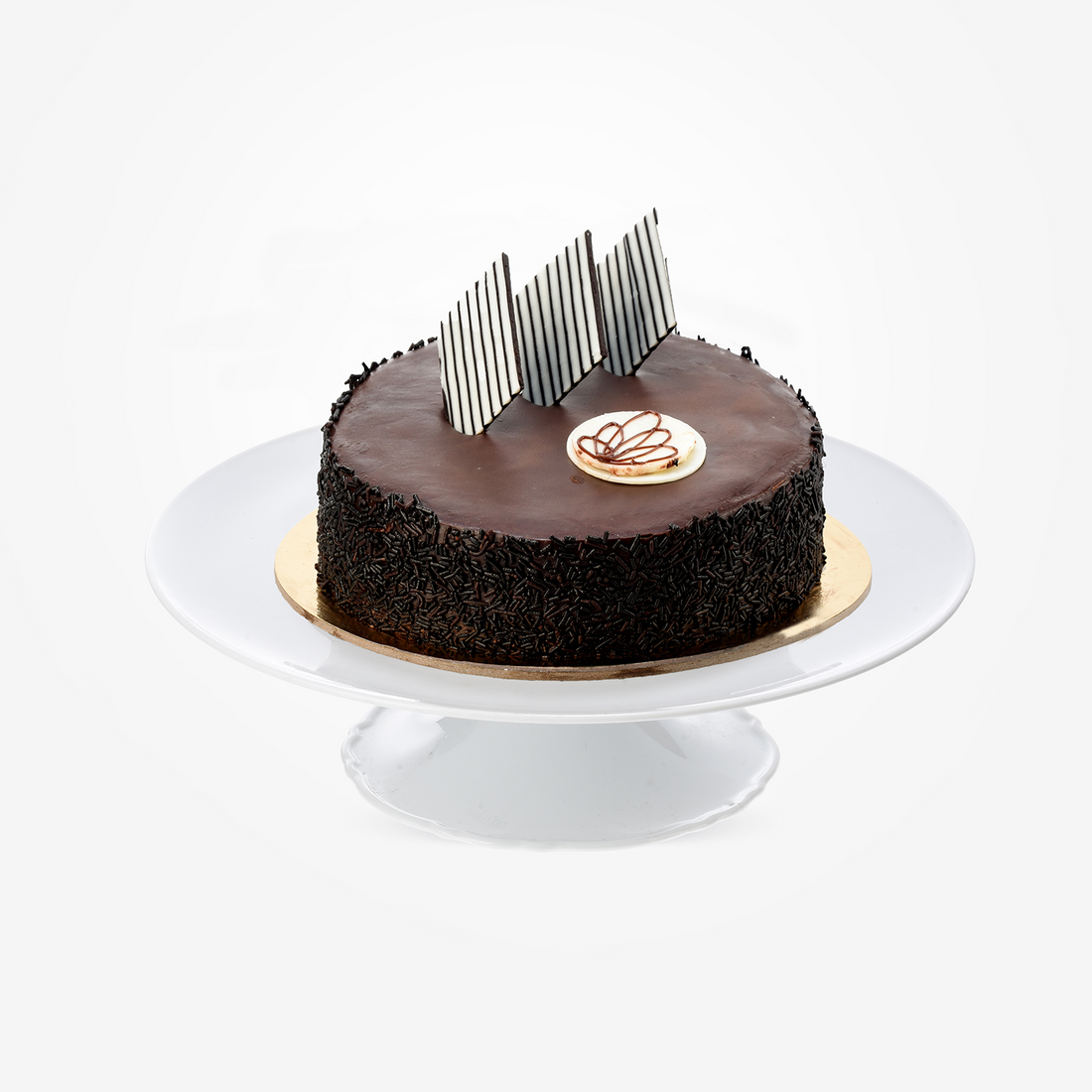 Rich chocolate cake with glossy ganache, chocolate shavings, striped shards, and heart drizzle on white stand.