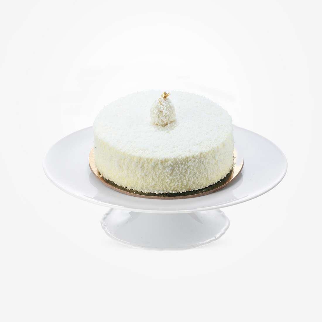 White coconut cake topped with gold leaf, elegantly displayed on a white cake stand.