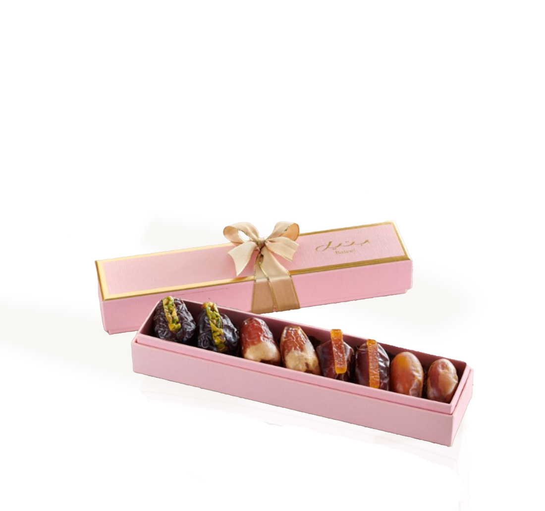 Elegant pink gift box with gold trim, holding assorted gourmet dates.