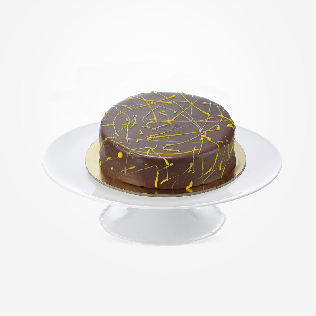 Rich chocolate cake with golden drizzle, elegantly displayed on white cake stand.