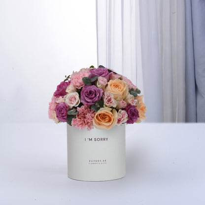 Pastel pink, purple, and peach roses in white box reading "I&