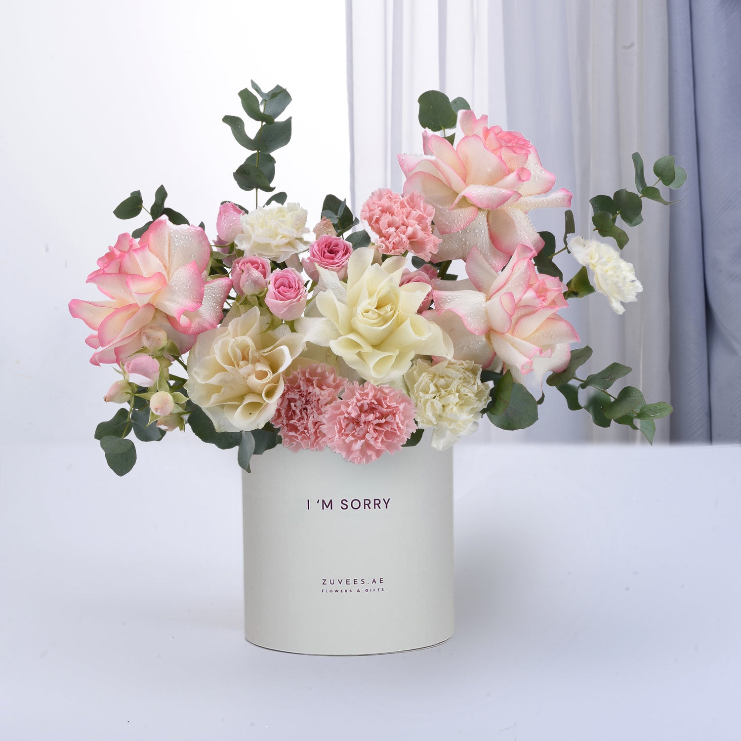 Soft pink and white roses, carnations, and eucalyptus in minimalist white vase with “I&