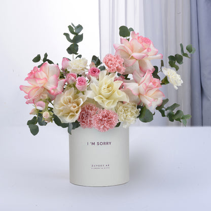 Soft pink and white roses, carnations, and eucalyptus in minimalist white vase with “I&