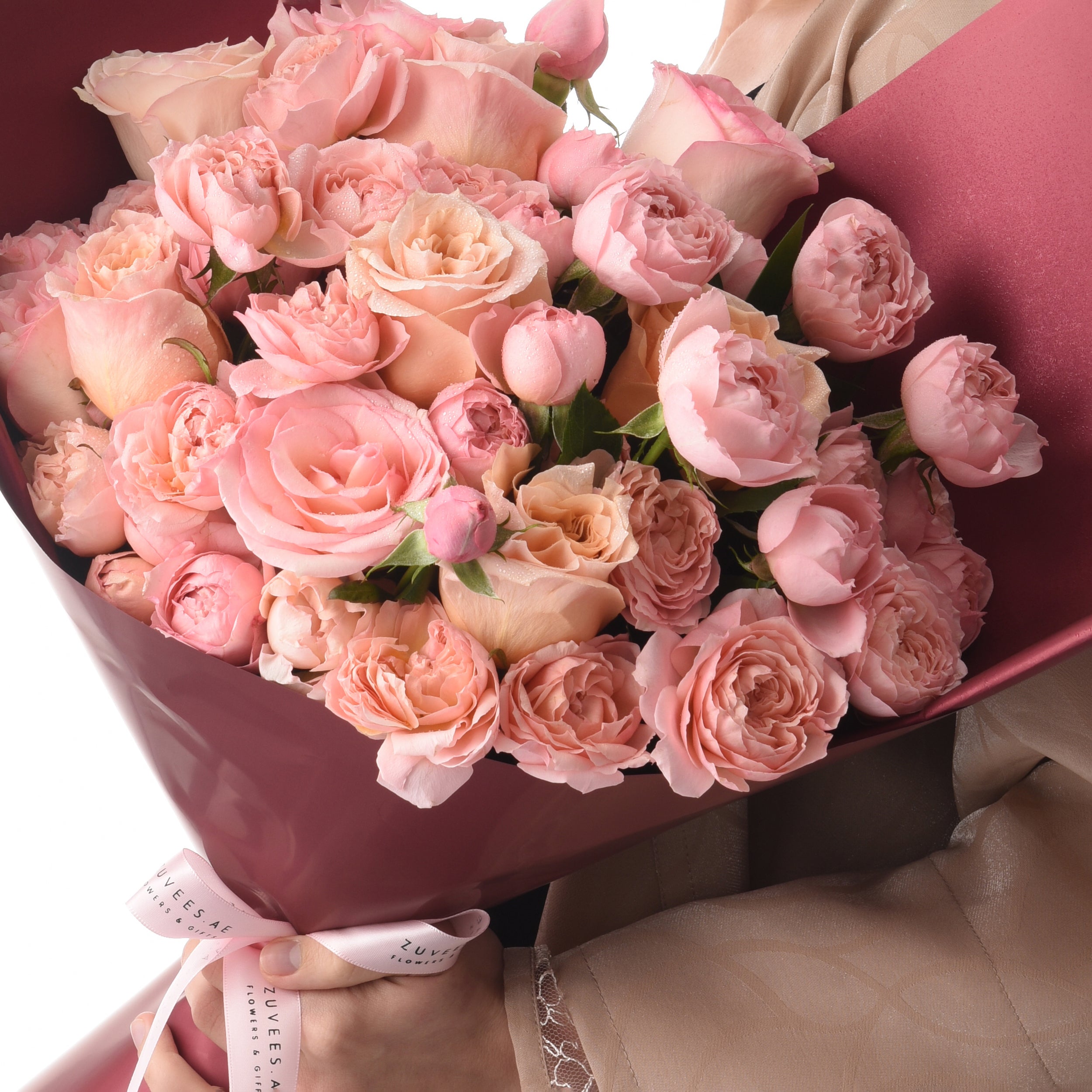 Luxurious pink rose bouquet with dewdrops, elegantly wrapped in satin, held gently for gifting.