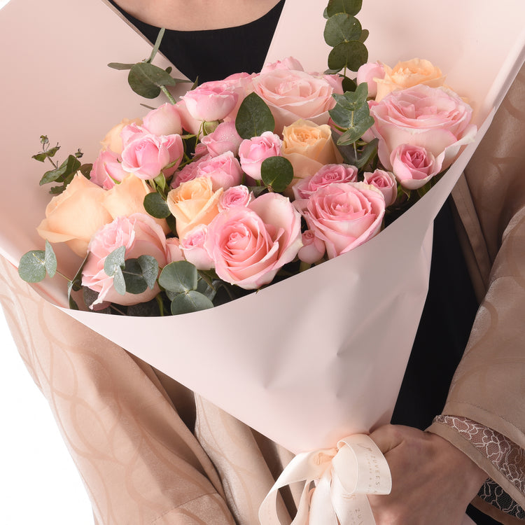 Soft pink and peach roses with eucalyptus, elegantly wrapped in blush paper.