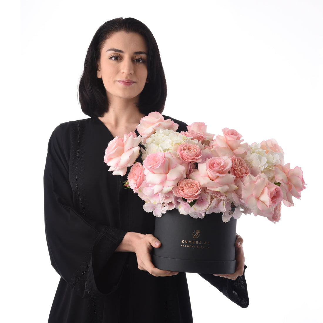 Elegant woman holds lush pink rose and hydrangea bouquet in sleek black box.