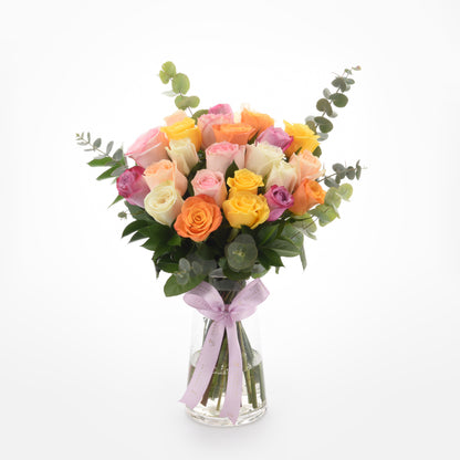 Vibrant multicolor roses in clear vase, accented with eucalyptus and lavender ribbon.