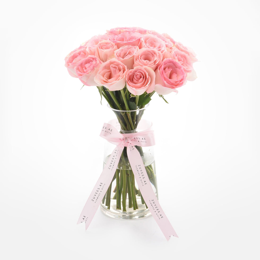 Soft pink roses in clear vase, elegantly tied with branded ribbon.