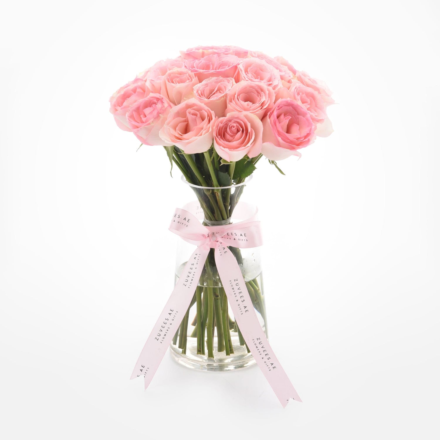 Soft pink roses in clear vase, elegantly tied with branded ribbon.