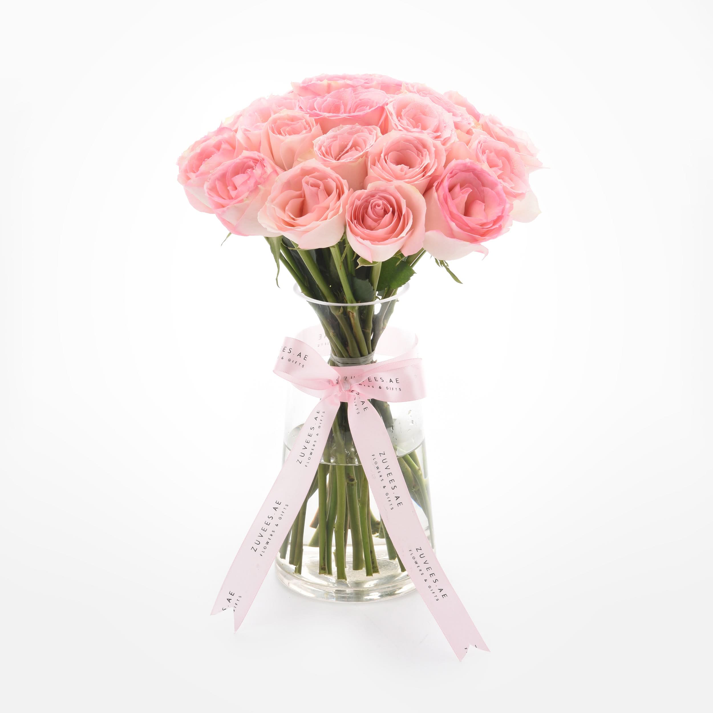 Soft pink roses in clear vase, elegantly tied with branded ribbon.