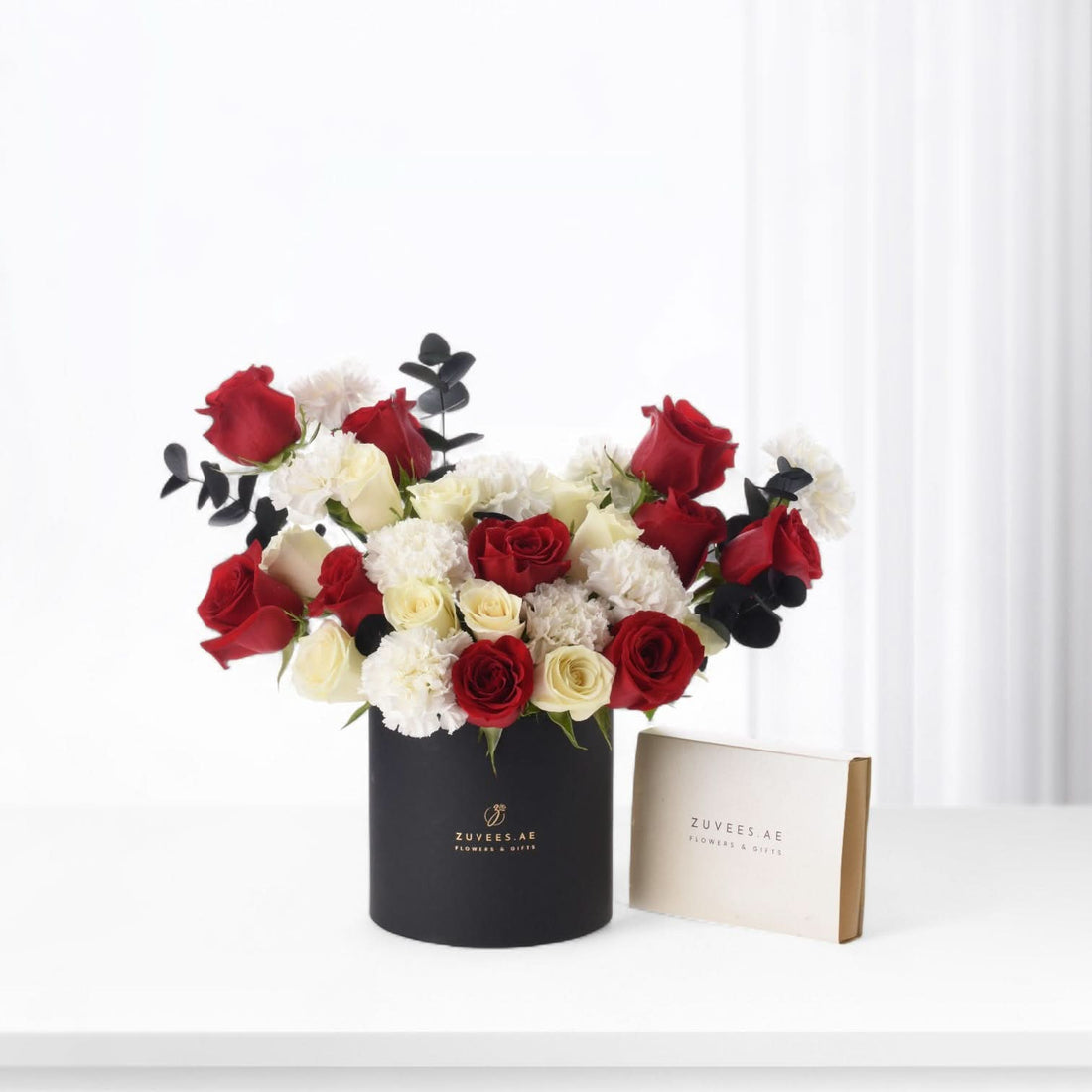 Bold red, white roses and carnations in sleek black vase with branded gift box.