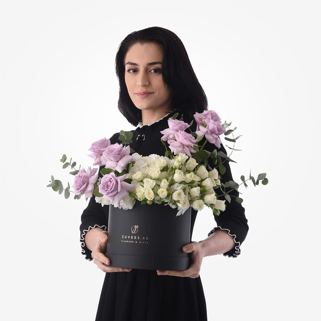 Elegant woman holds black box filled with lavender and ivory roses, accented with eucalyptus.