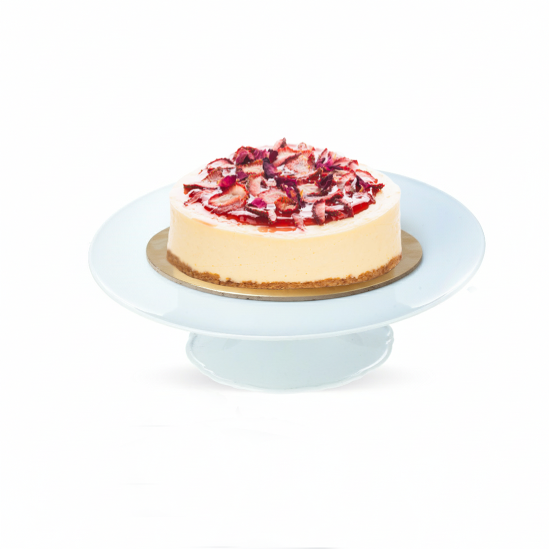 Creamy cheesecake topped with sliced strawberries and rose petals on light blue cake stand.