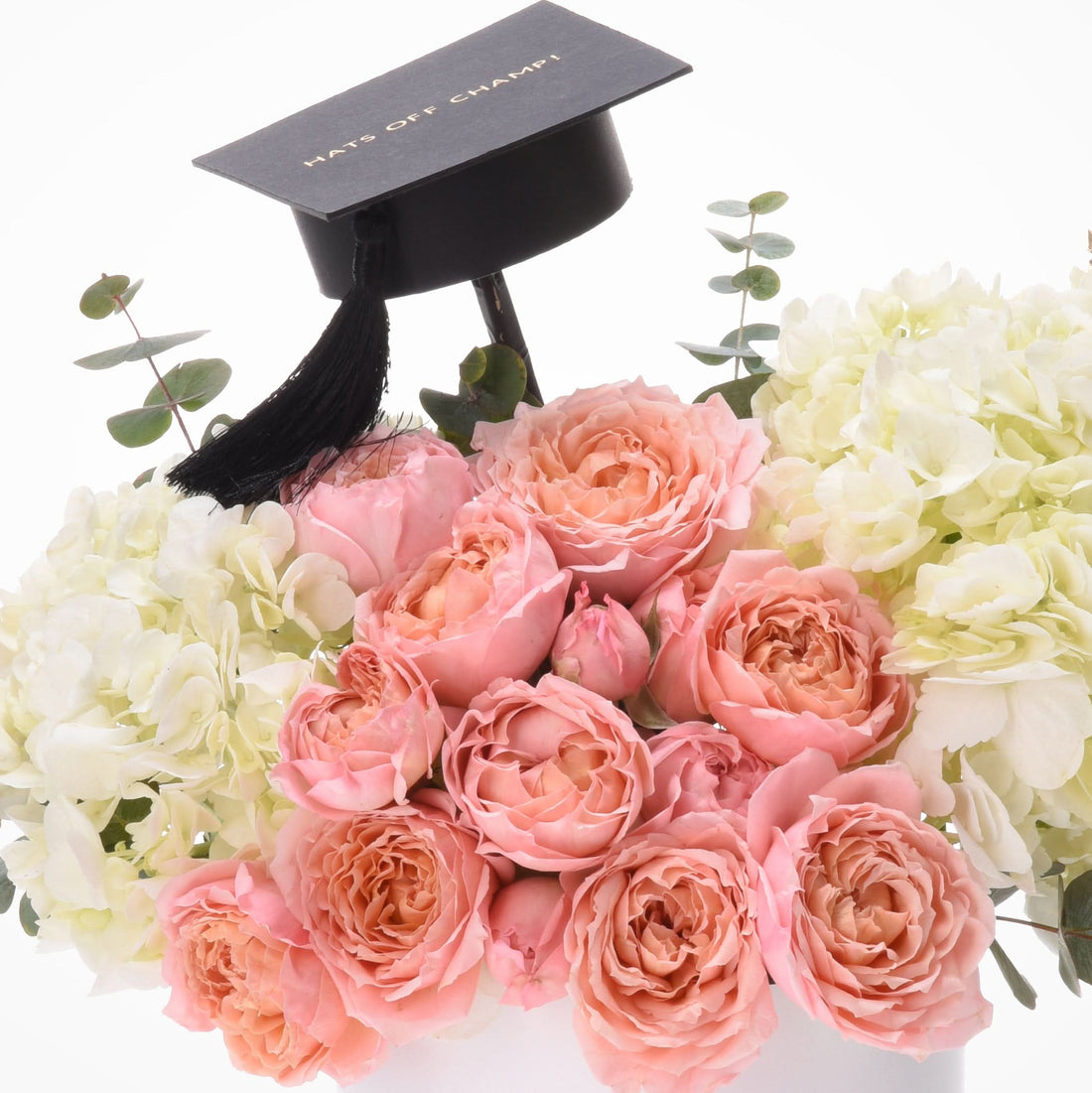 Pink roses, white hydrangeas, eucalyptus, black graduation cap with "HATS OFF CHAMP!" gold text.