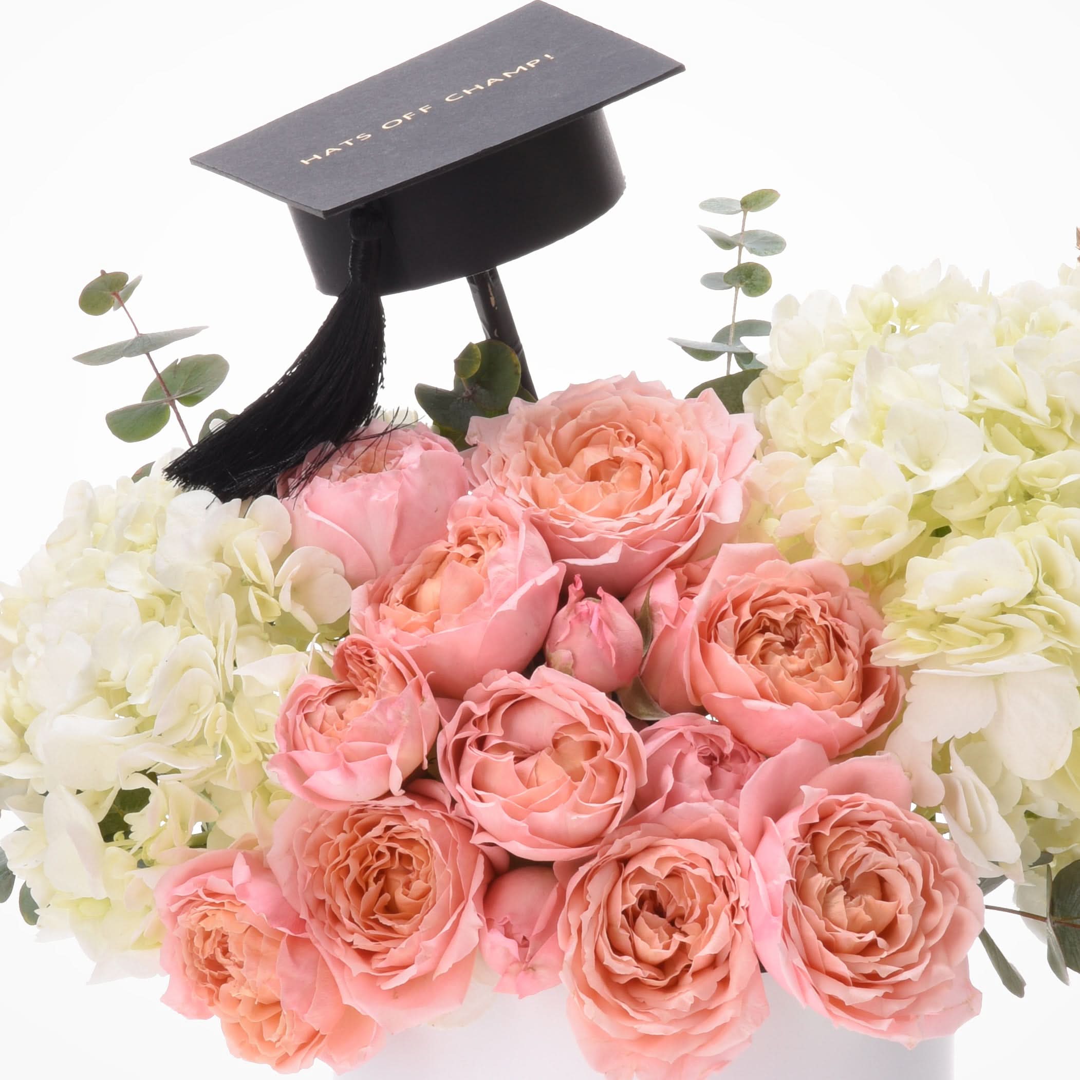 Pink roses, white hydrangeas, eucalyptus, black graduation cap with "HATS OFF CHAMP!" gold text.